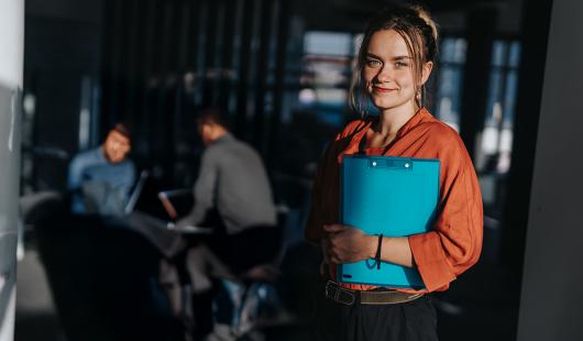 Femme avec dossier dans les bras et une équipe derrière